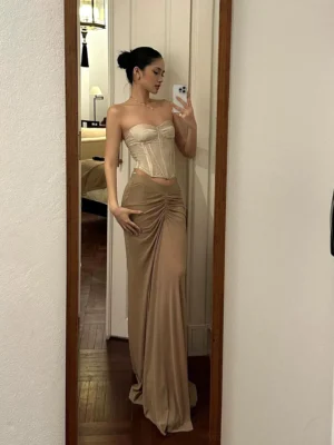 Taupe coffee color ruched maxi skirt with V-shaped waist styled with a satin corset in a hotel mirror outfit view
