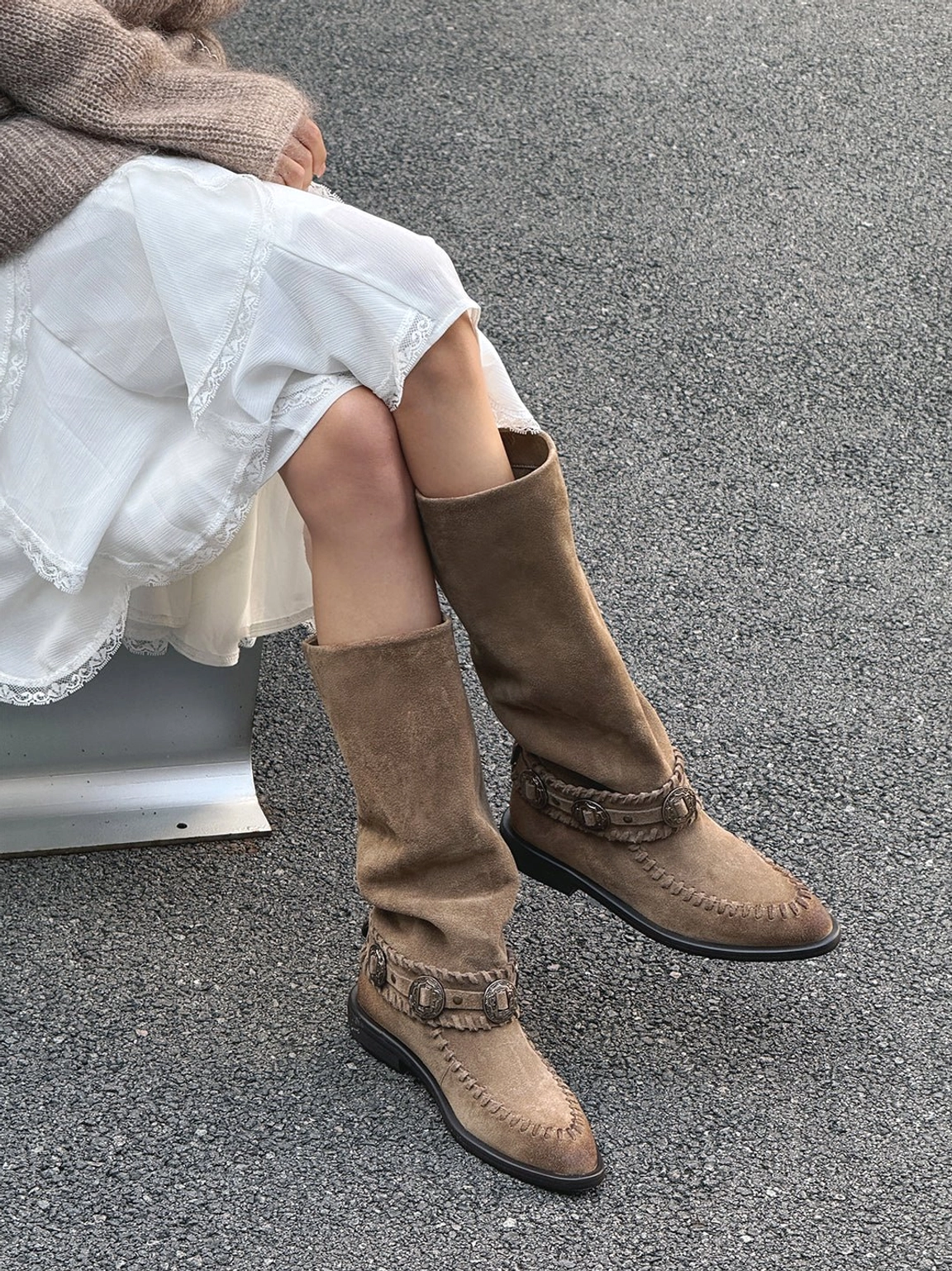 Taupe suede western knee-high boots worn with a white ruffled skirt and knit sweater in a casual outdoor Korean-inspired outfit