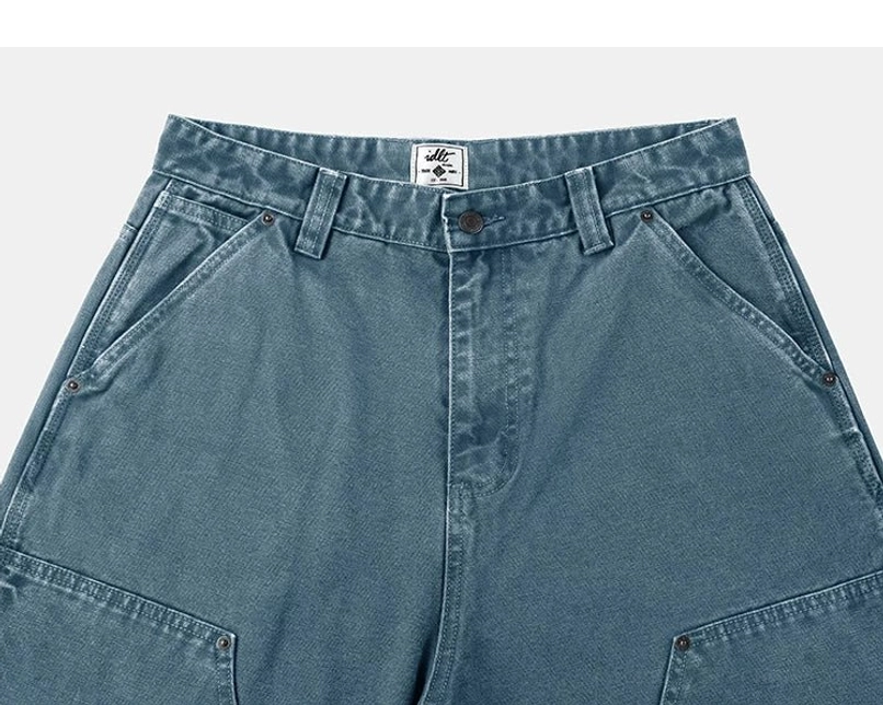 Teal carpenter denim pants waistband close-up with belt loops, button closure, riveted pockets, and utility styling