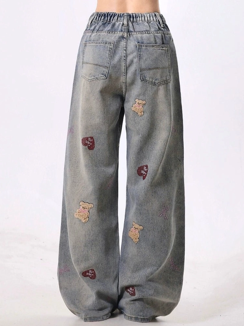 Rear view of teddy bear embroidered wide-leg jeans showing elasticated back waistband, two patch pockets, distressed denim details, and relaxed streetwear fit