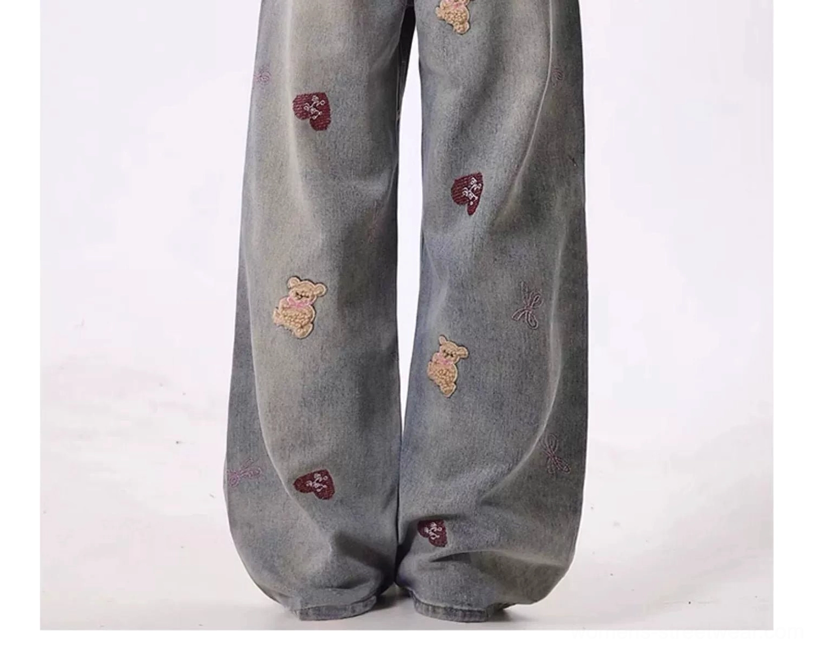 Close-up of teddy bear and red heart embroidery with tiny bow details on vintage distressed wide-leg denim jeans