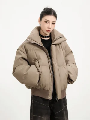 Teddy Brown oversized cropped winter puffer jacket with hidden zipper snap placket and high collar worn with dark denim