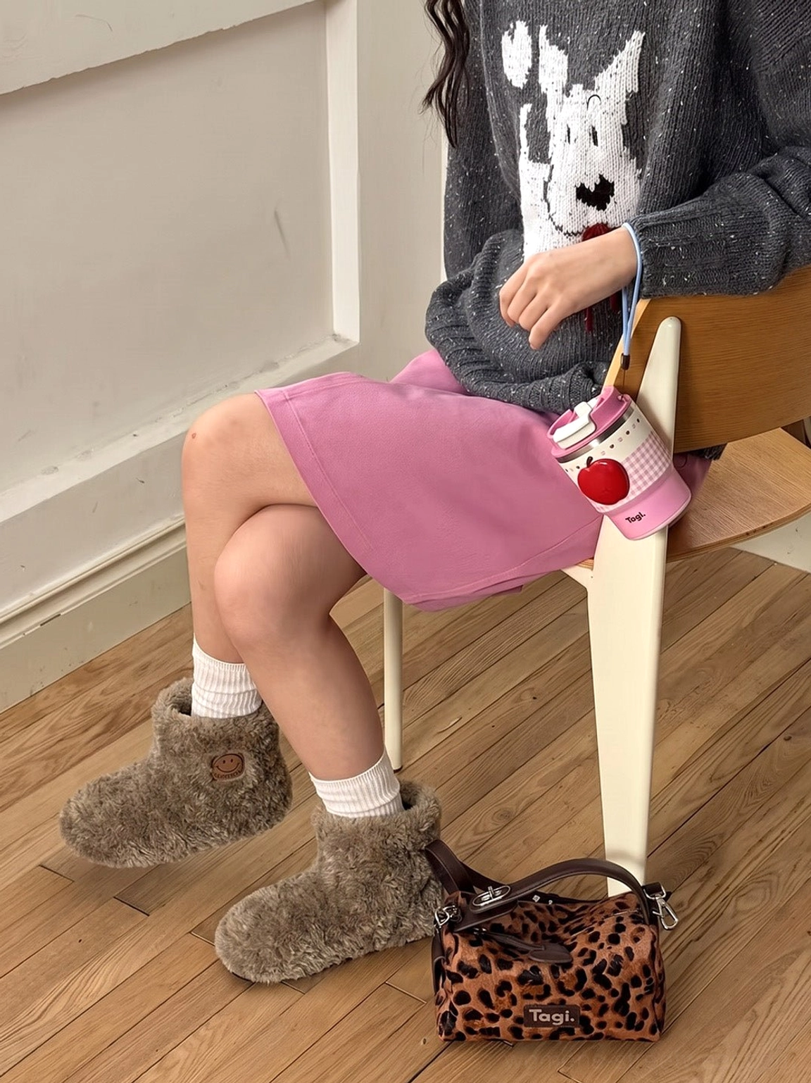Model styling khaki teddy fleece platform ankle boots with white socks knit sweater and pink mini skirt indoors
