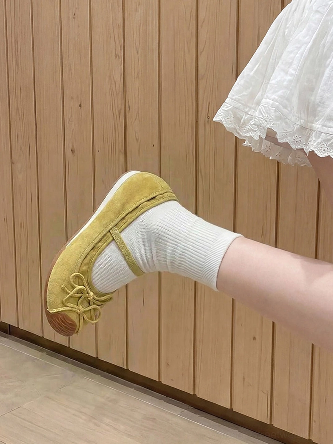Mustard yellow bow Mary Jane ballet flats worn with white crew socks in a casual streetwear outfit