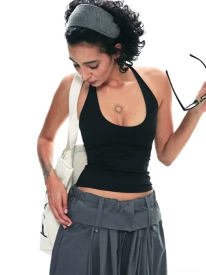 Black textured halter backless cropped tank top styled with gray wide leg cargo pants in a white studio