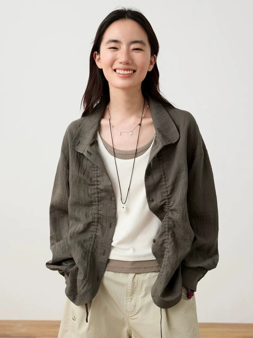 Dark gray textured Mandarin collar button-up shirt layered over a white camisole with relaxed beige shorts in a minimalist streetwear studio outfit