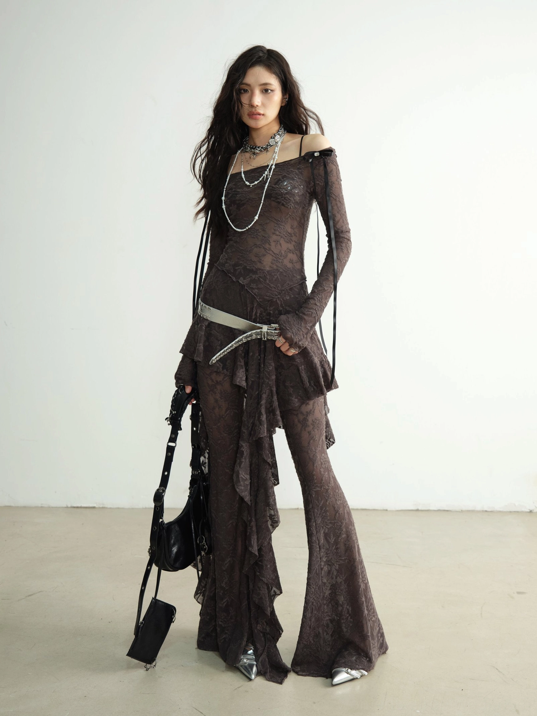 Three quarter view of off shoulder textured lace dance pant set with fitted sleeves silver belt and pointed shoes