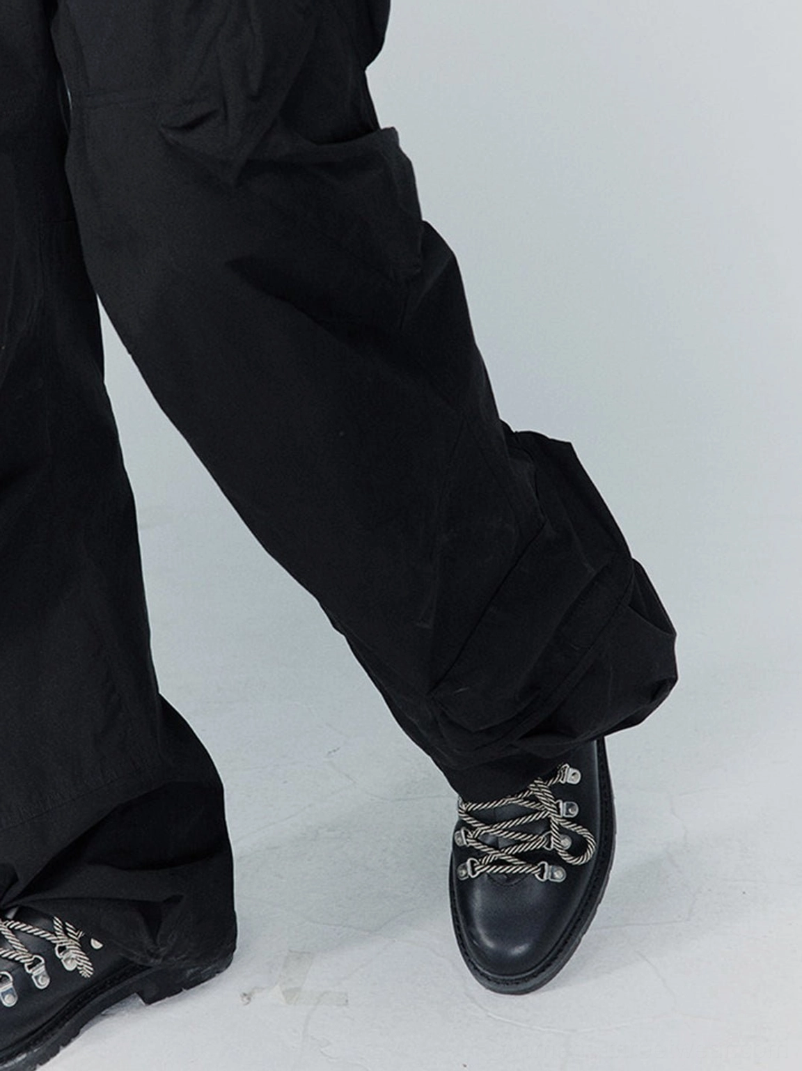 Black metal-eyelet Derby shoes paired with baggy black cargo pants in an urban streetwear look