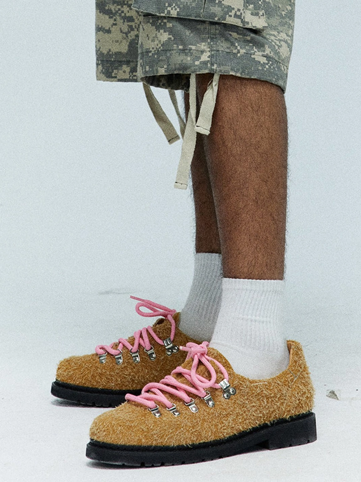 Khaki suede metal-eyelet Derby shoes styled with white socks and cropped camouflage cargo shorts