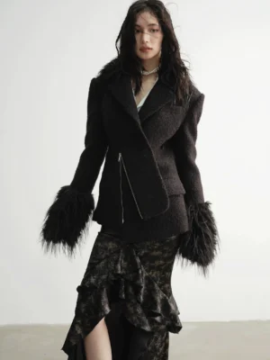 Close up view of a textured tailored coat with wide notched lapel cinched waist exposed asymmetrical zipper and oversized faux fur cuffs