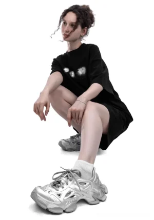 Metallic silver Time-Space platform clog sneakers styled with an oversized black streetwear outfit in a low-angle fashion look