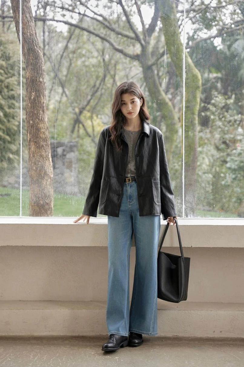 Full-body side view of a woman wearing a timeless loose fit black vintage leather jacket