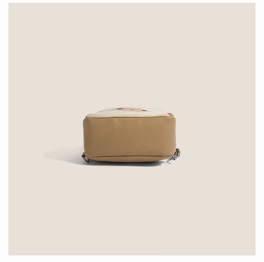 Overhead bottom view of a compact toast beige faux leather cat mini backpack showing the solid base, cuboid shape, rounded construction, and exposed side zipper detail