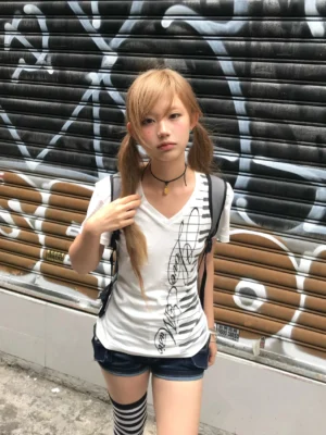 Treble clef piano key V-neck streetwear tee for women worn with denim shorts in front of a graffiti shutter