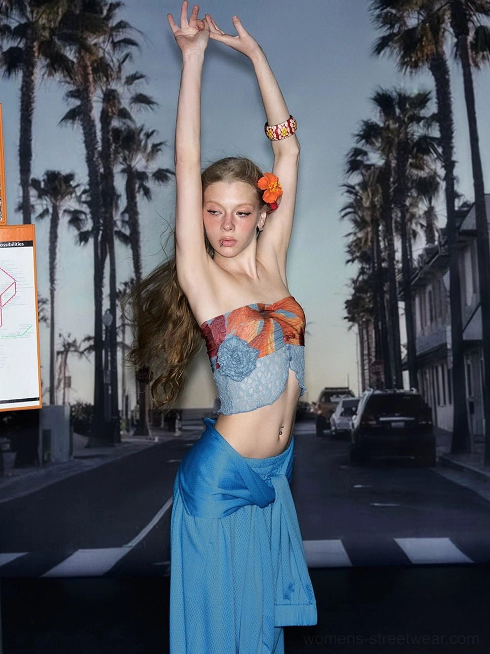 Side view of a tropical fruit print strapless crop top styled with a tied long skirt for coastal streetwear