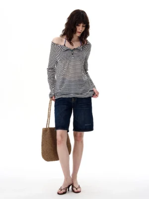 Black striped off-shoulder long sleeve top with twisted neckline worn as a relaxed streetwear outfit with denim shorts