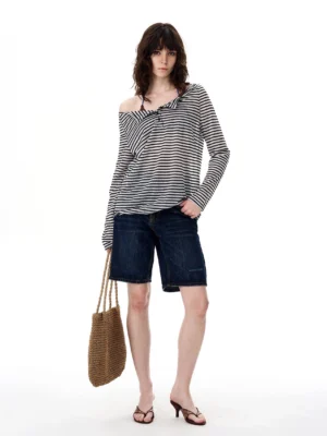 Black and white twist stripe off-shoulder long sleeve streetwear top styled with dark denim shorts in a full body front view