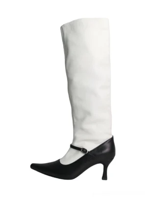 Front view of black and white two-tone pointed-toe knee-high streetwear boots with slouchy white shaft, black leather foot, ankle buckle strap, and slim curved heel