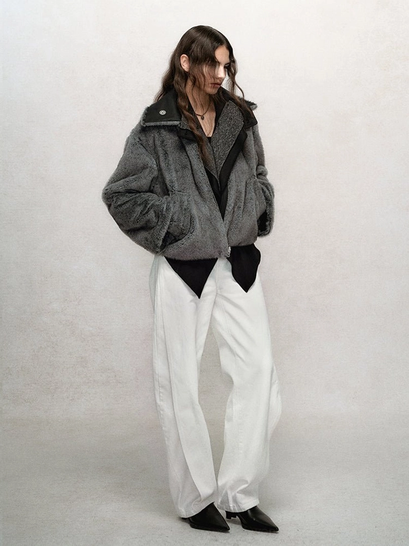 Two-tone cropped faux fur bomber jacket with dark gray body, contrasting black collar lining, front zipper, and cropped hem