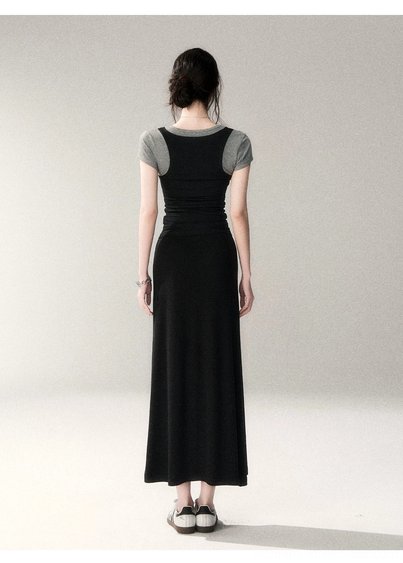 Full back view of a two-tone layered scoop neck top worn beneath a black maxi dress with visible contrast back panel and flat loafers