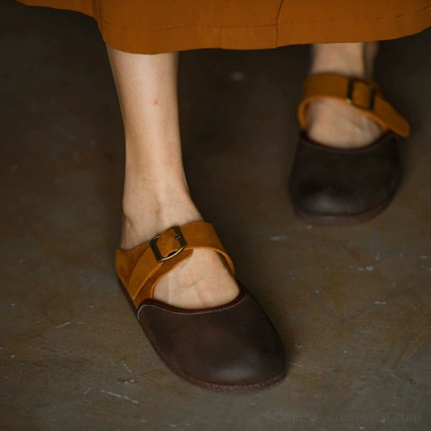 Two-tone leather Mary Jane flats worn on dark wood floor with rounded brown toe and flat sole