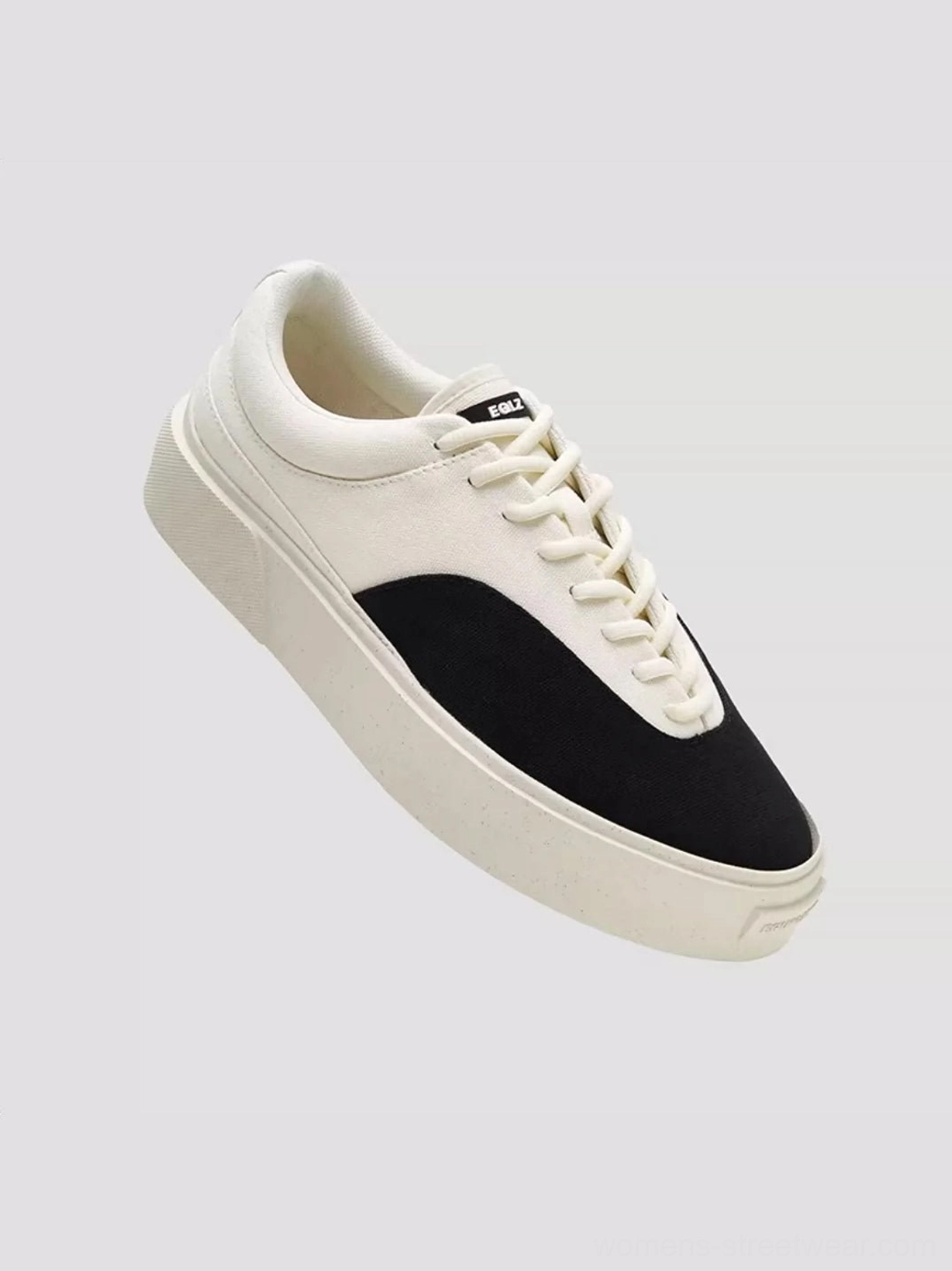 Three-quarter view of low-top two-tone canvas skate shoes with black toe panel off-white upper flat laces and thick platform sole