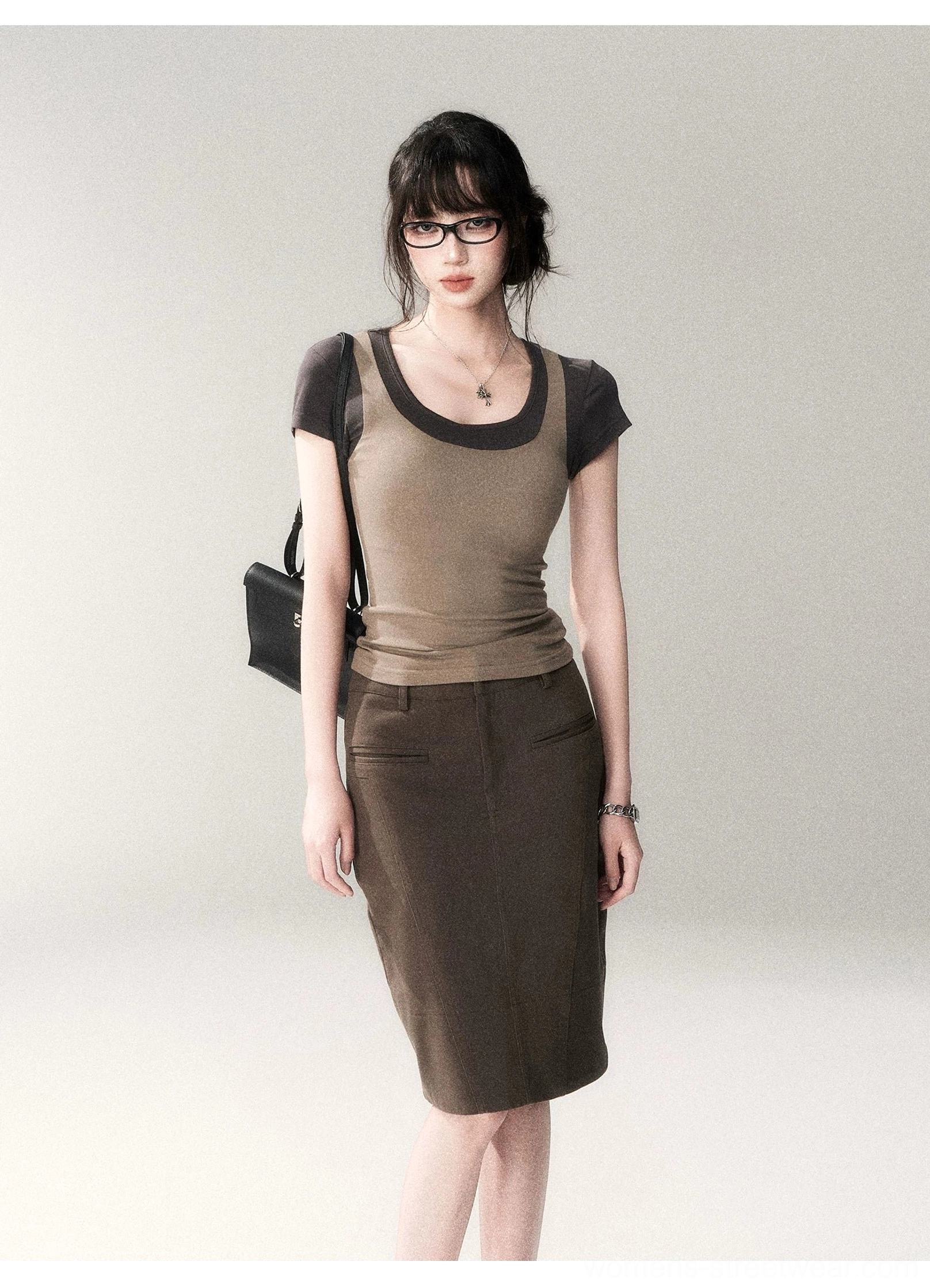 Full front view of a two-tone scoop neck fitted top with dark contrast trim styled with a brown tailored midi pencil skirt and minimalist accessories