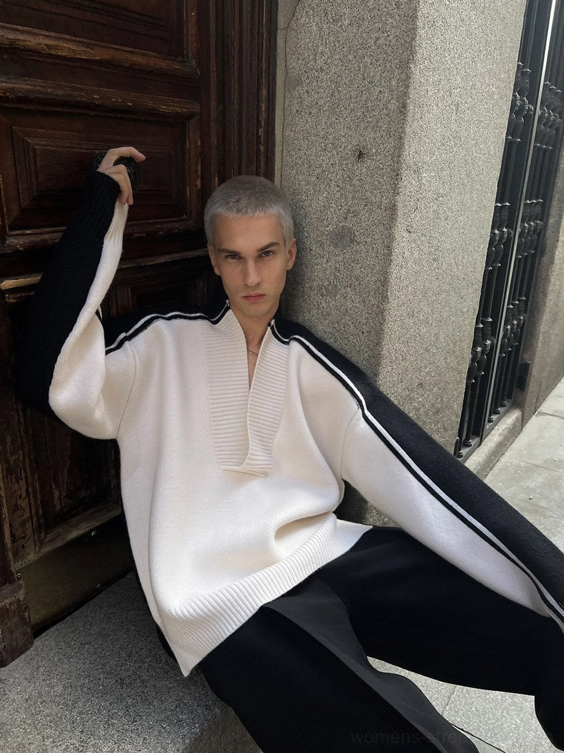 Full body view of two tone V-neck racing stripe sweater with white front panel and black striped sleeves