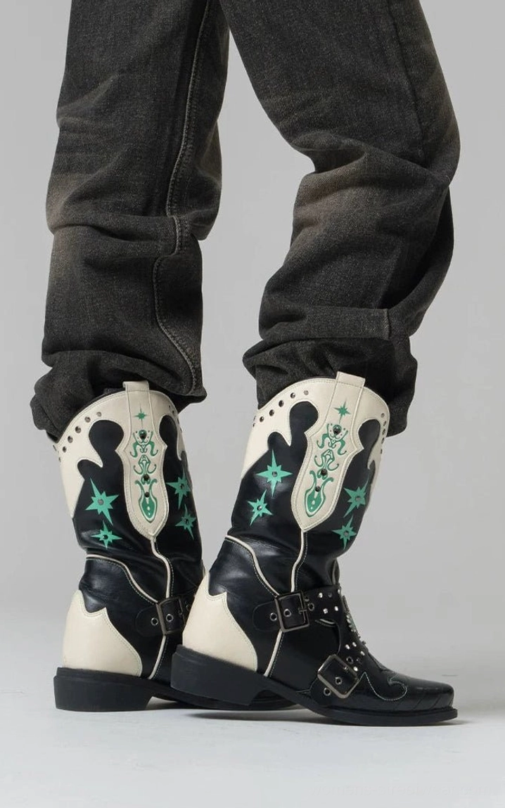 Back view of women's two-tone western cowboy boots worn with rolled dark denim jeans and detailed with green embroidery and studded harness straps