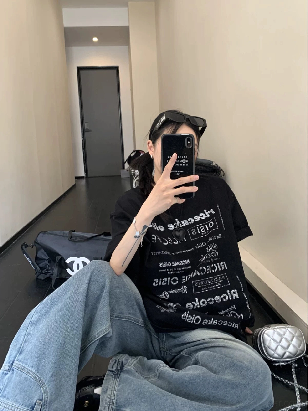 Black oversized graphic typography t-shirt styled with wide-leg blue jeans in a casual streetwear outfit