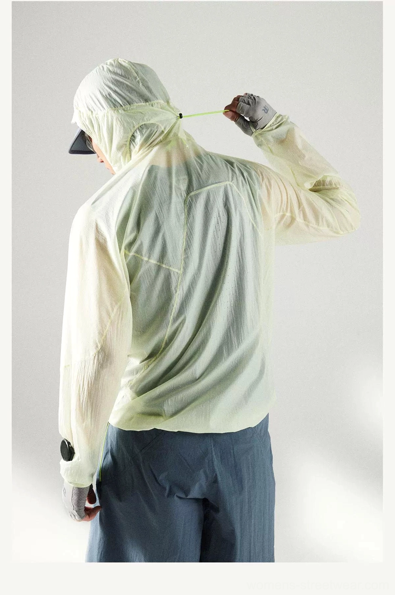 Rear full-body view of a model wearing the Lemon Green ultra-light UV protection hooded windbreaker with crinkled sheer fabric and thumbhole cuffs