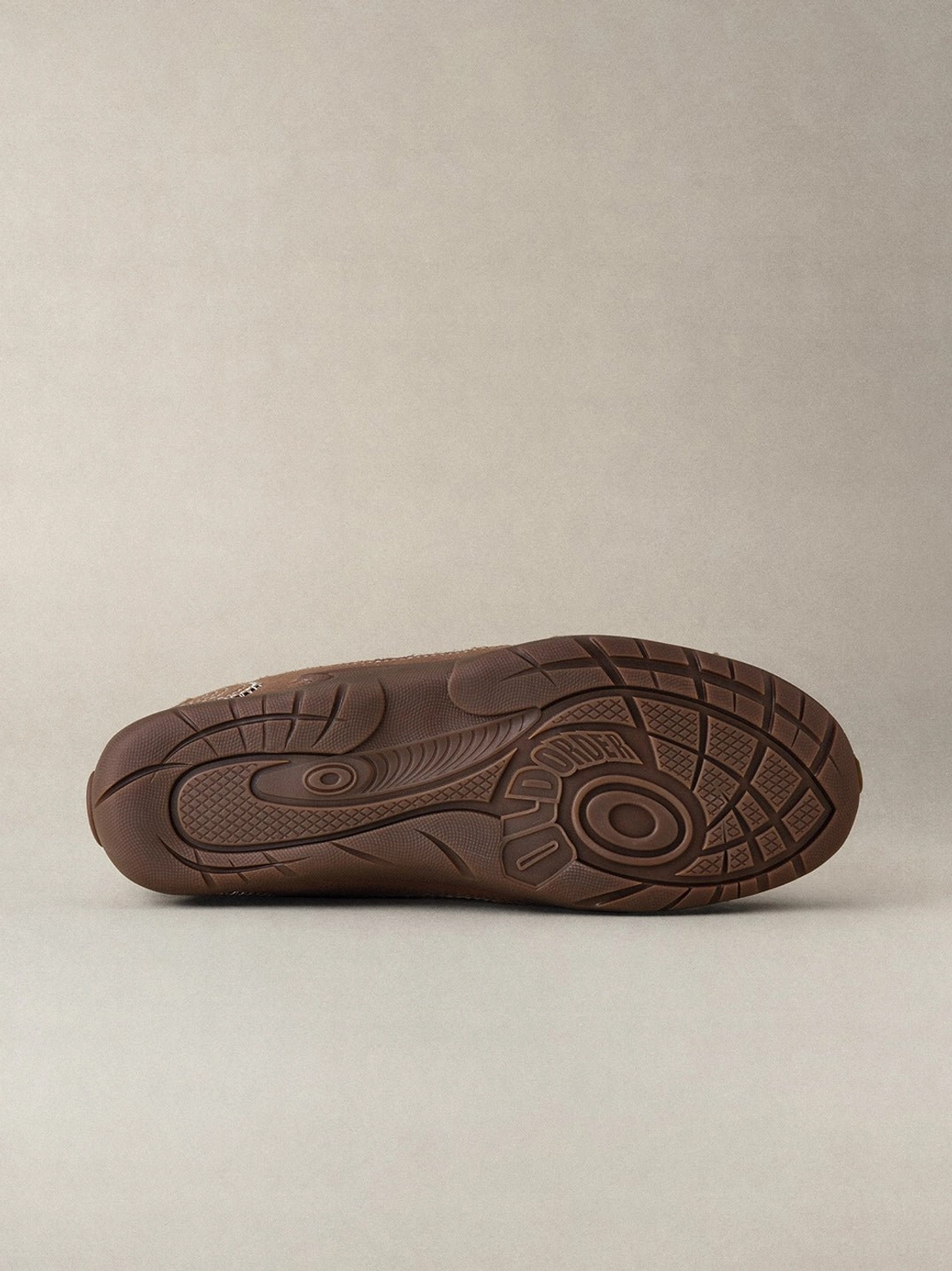 Unisex brown retro streetwear trainers with cream swirl detailing, rounded toe, and slim tonal gum sole