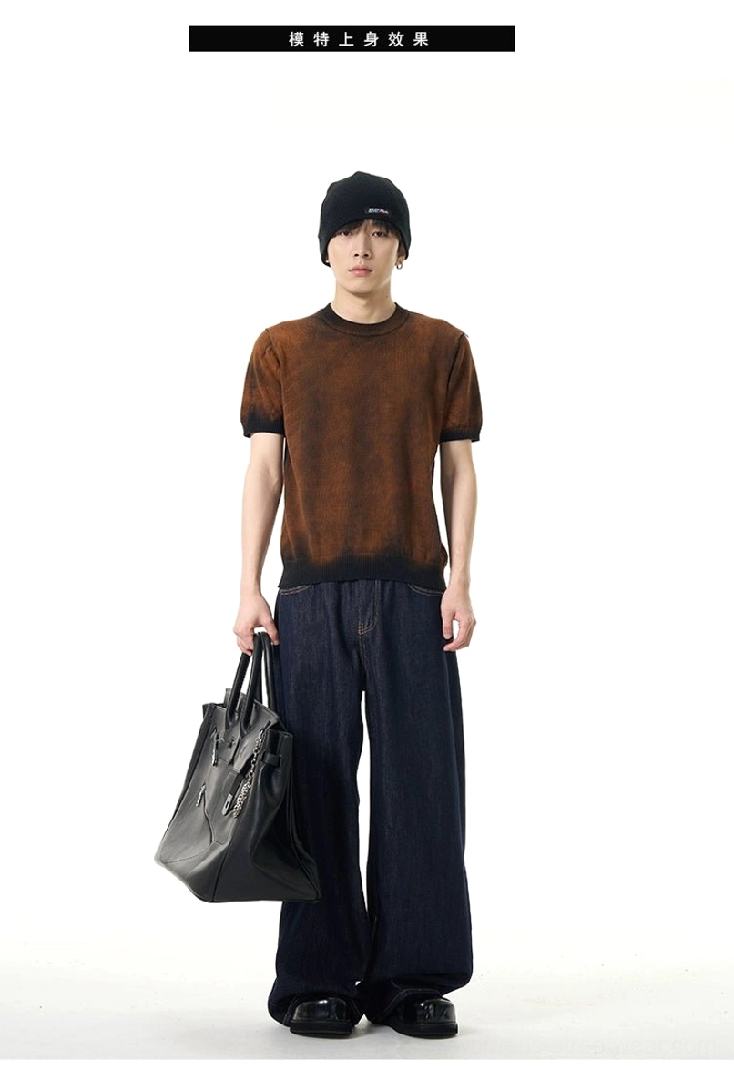 Male model wearing relaxed unisex dark wash wide-leg streetwear jeans with a brown gradient tee, black beanie, and leather tote bag