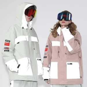 Unisex reflective panel ski jackets in white and pink with cargo pockets, hood drawcords, sleeve patches, and ski goggles on studio models