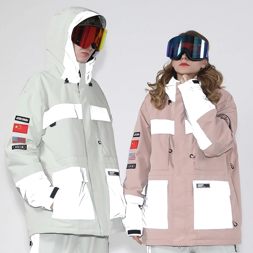 Unisex reflective panel ski jackets in white and pink with cargo pockets, hood drawcords, sleeve patches, and ski goggles on studio models