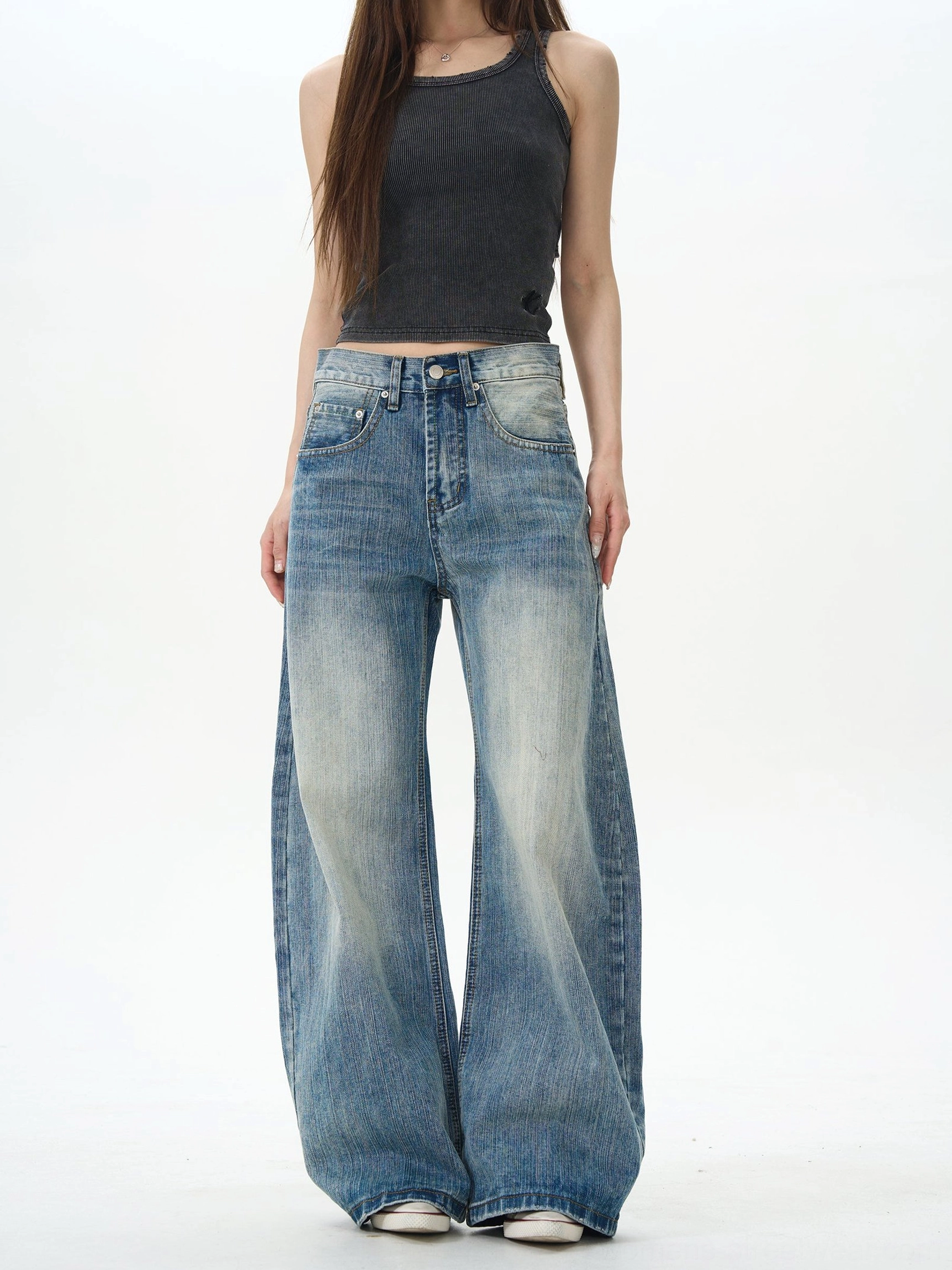 Front view of unisex retro wide-leg denim jeans with faded vintage blue wash, high-waisted fit, and classic streetwear silhouette styled with a black slim tank top