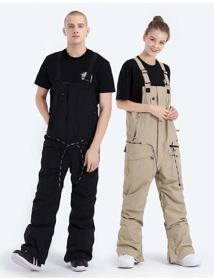 Black and light tan unisex utility bib snow pants in a full-body front studio view with high bib coverage and front zippered utility pockets