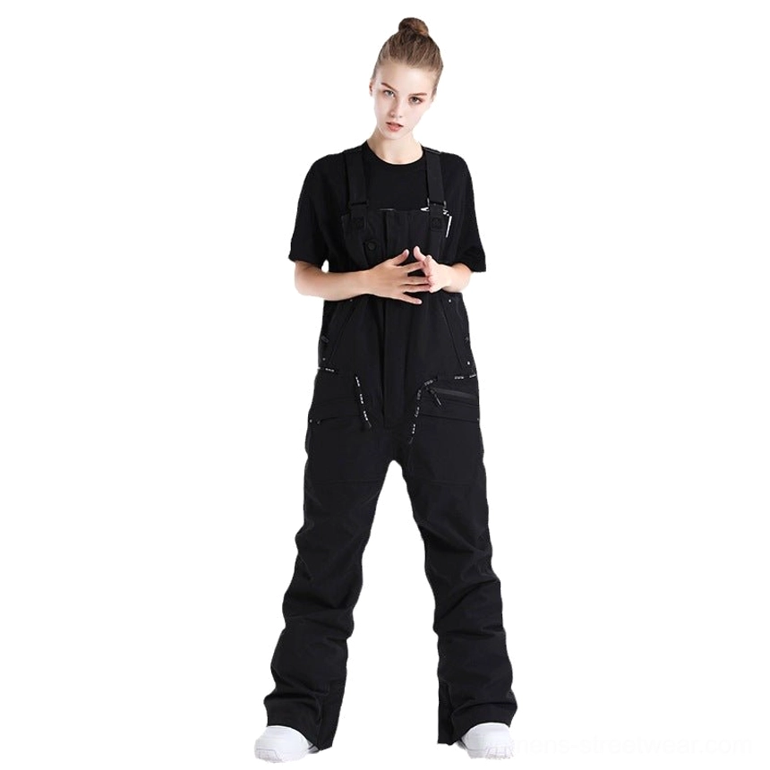 Black unisex waterproof utility bib snow pants shown in a full-body front studio view with adjustable suspenders and flared streetwear snow pants silhouette