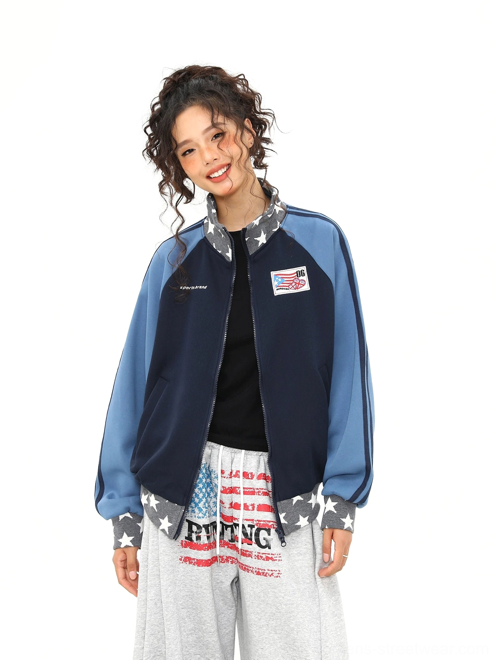 Unzipped star print colorblock varsity track jacket layered over a black top with chest patch and patterned cuffs