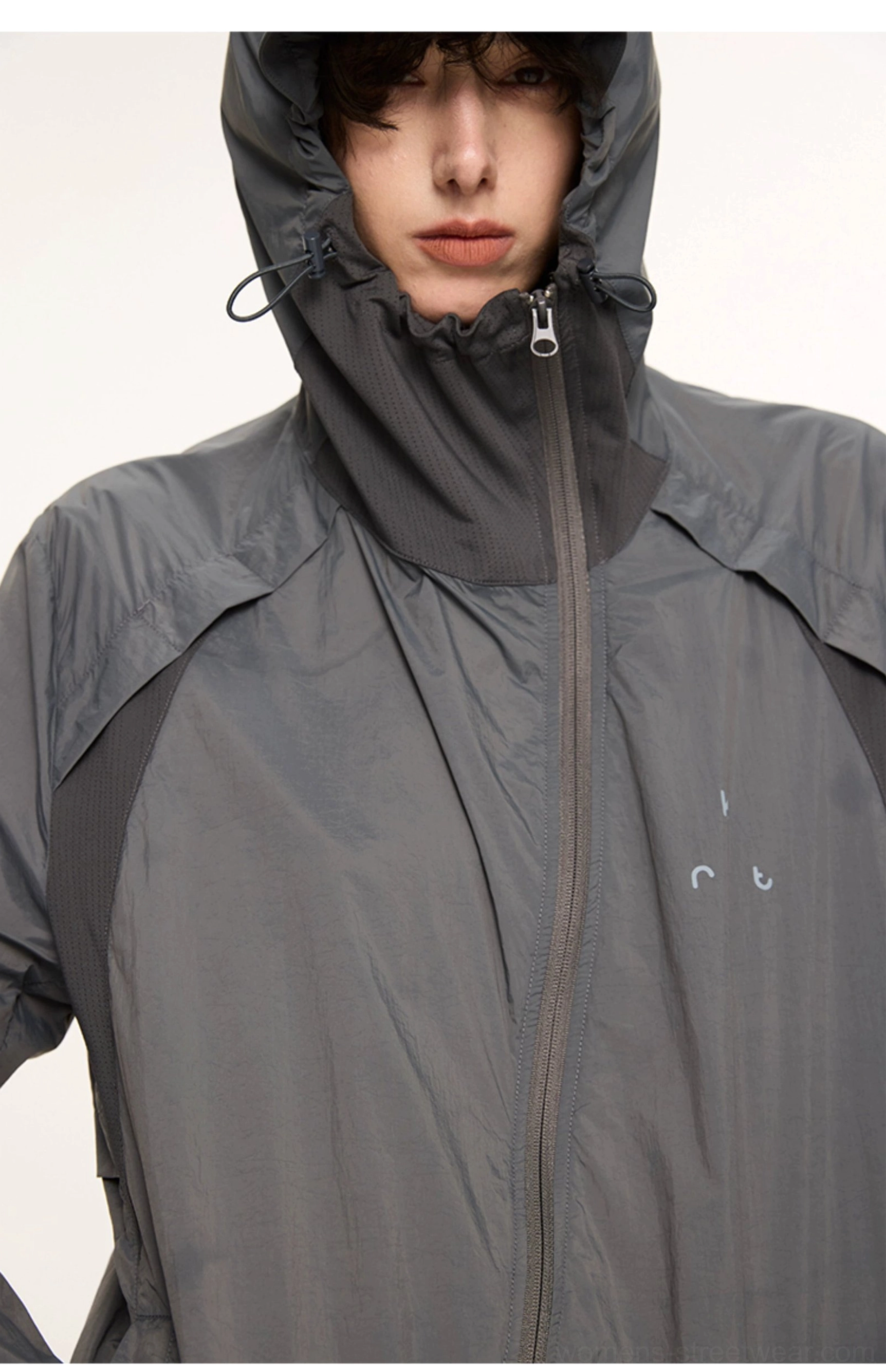 Close-up of dark gray UPF 50 hooded techwear jacket with full zip high collar drawcord and chest detail