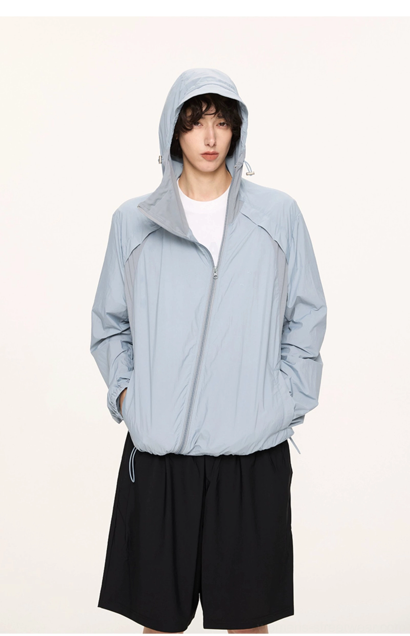 Dusty blue UPF 50 lightweight hooded sun jacket styled with black shorts in a relaxed streetwear outfit