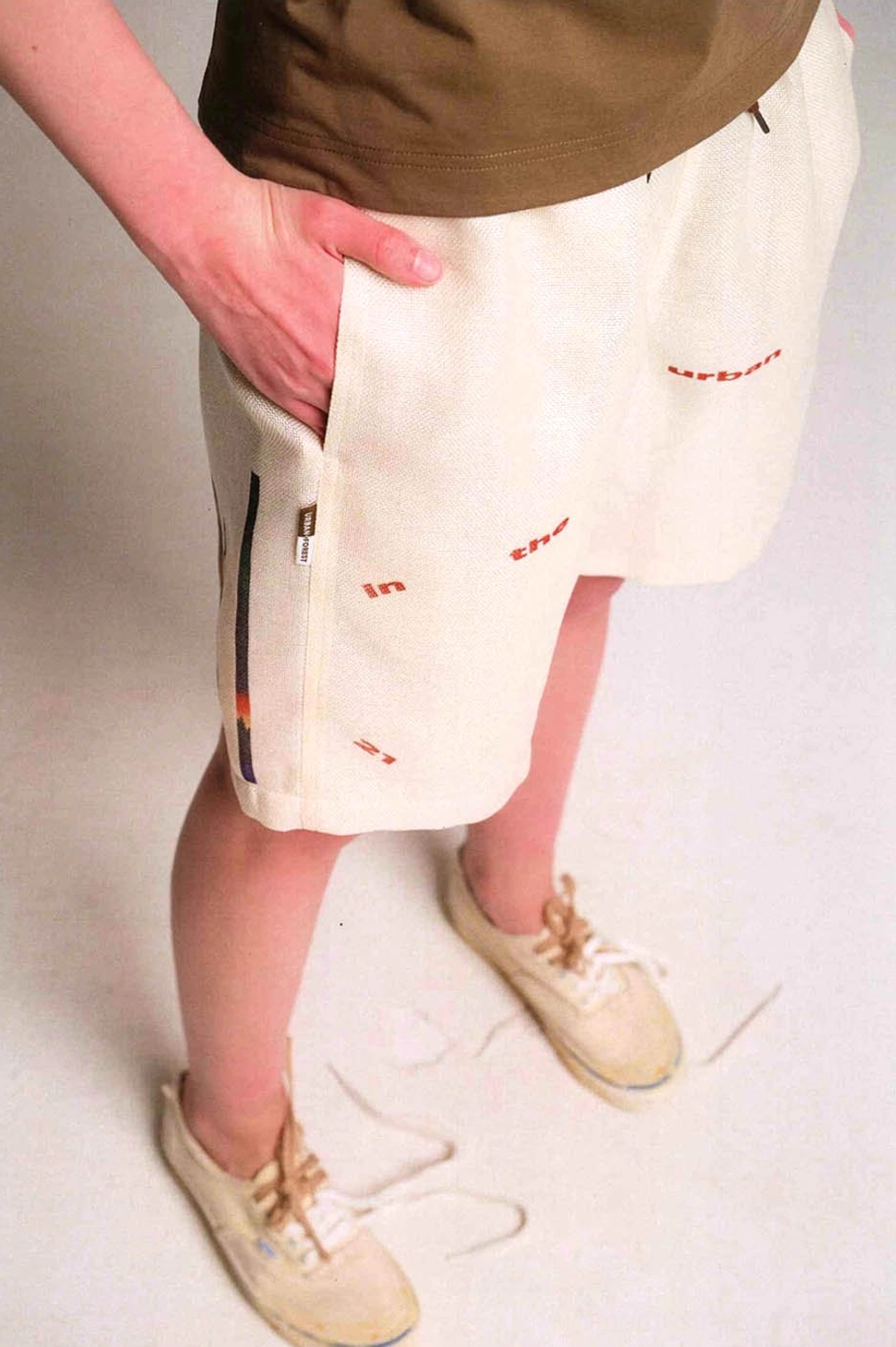 Apricot Urban Forest graphic sweat shorts close front view showing zip side pocket and small text graphics