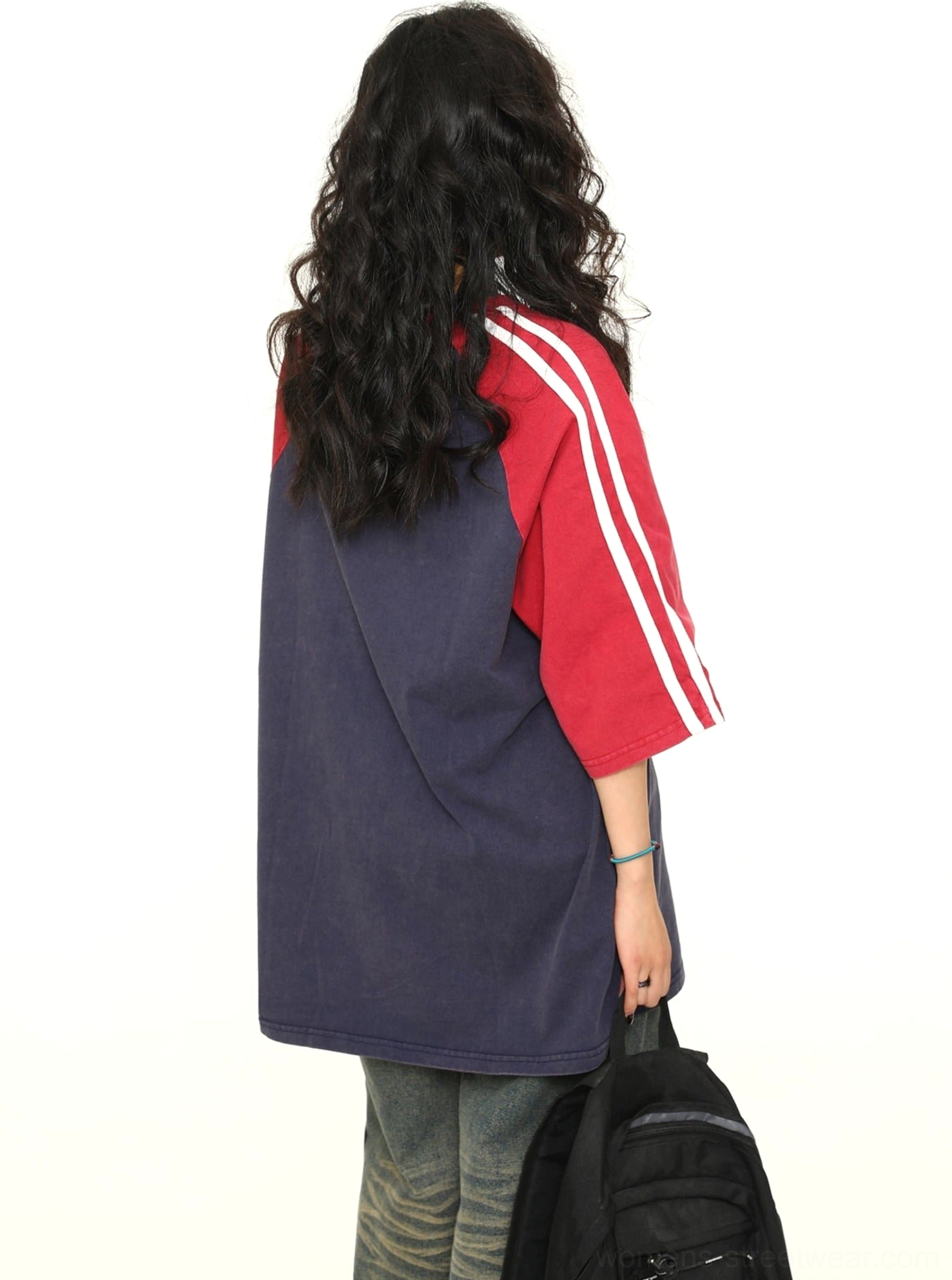 Back view of a loose varsity raglan graphic T-shirt with red sleeves, white stripe accents, and a navy body
