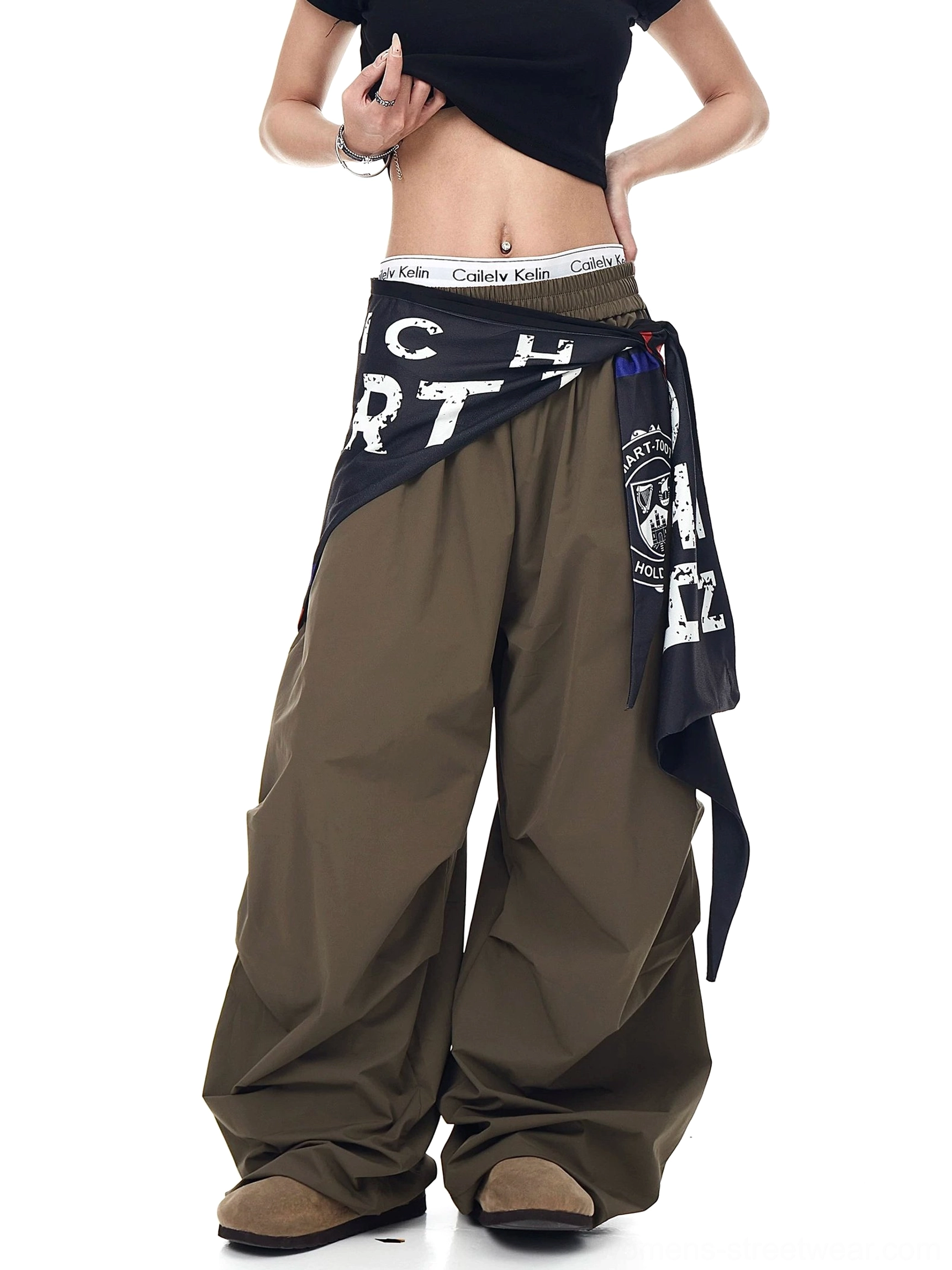 Side view of army green wide-leg parachute cargo pants showing the relaxed drape, layered varsity scarf, and oversized streetwear silhouette