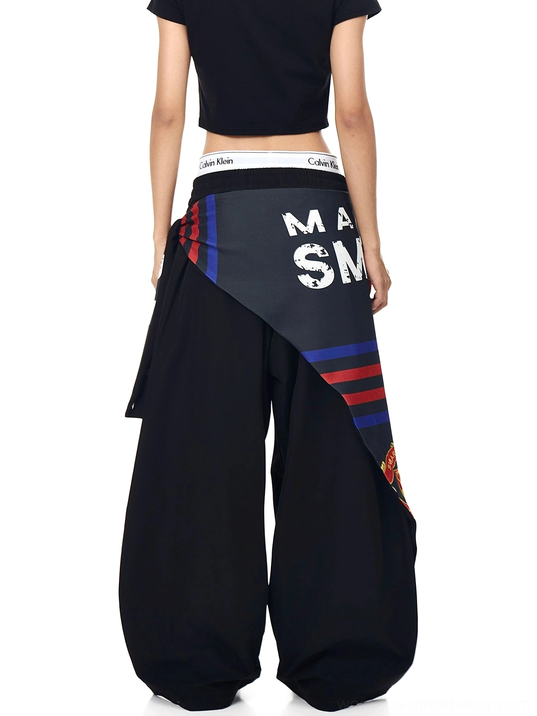 Back view of black varsity scarf parachute cargo pants with an oversized loose-leg silhouette, graphic scarf panel, and elastic waistband