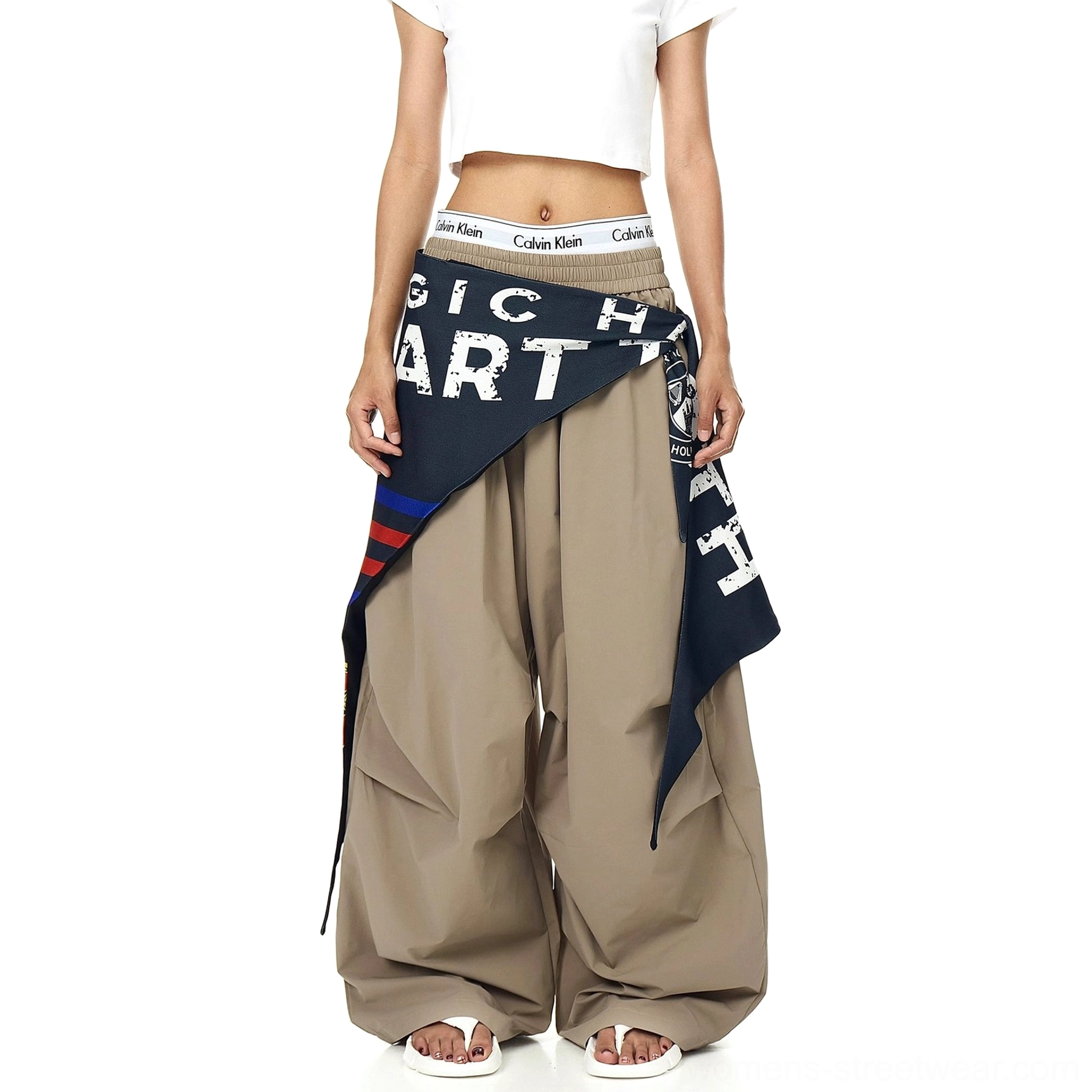 Deconstructed varsity parachute pants with ultra-wide legs, flowing fabric volume, utility-inspired styling, and detachable scarf detail