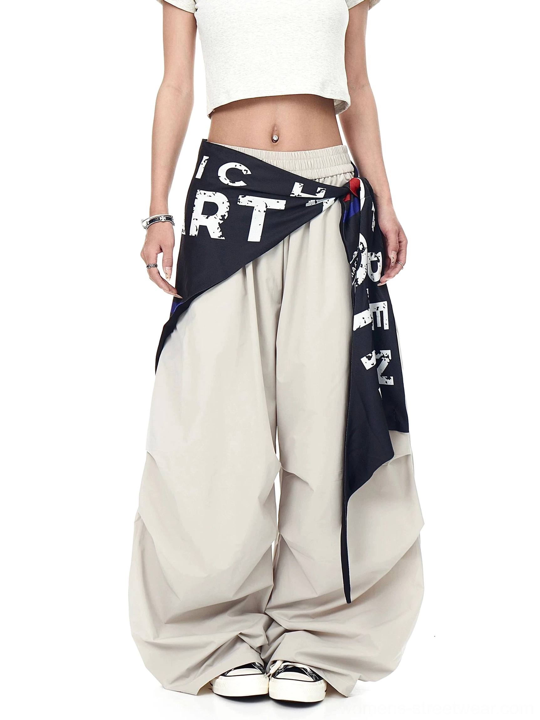 Front view of khaki varsity wide-leg cargo pants with an elastic waistband, printed scarf layer, oversized parachute fit, and casual sneakers