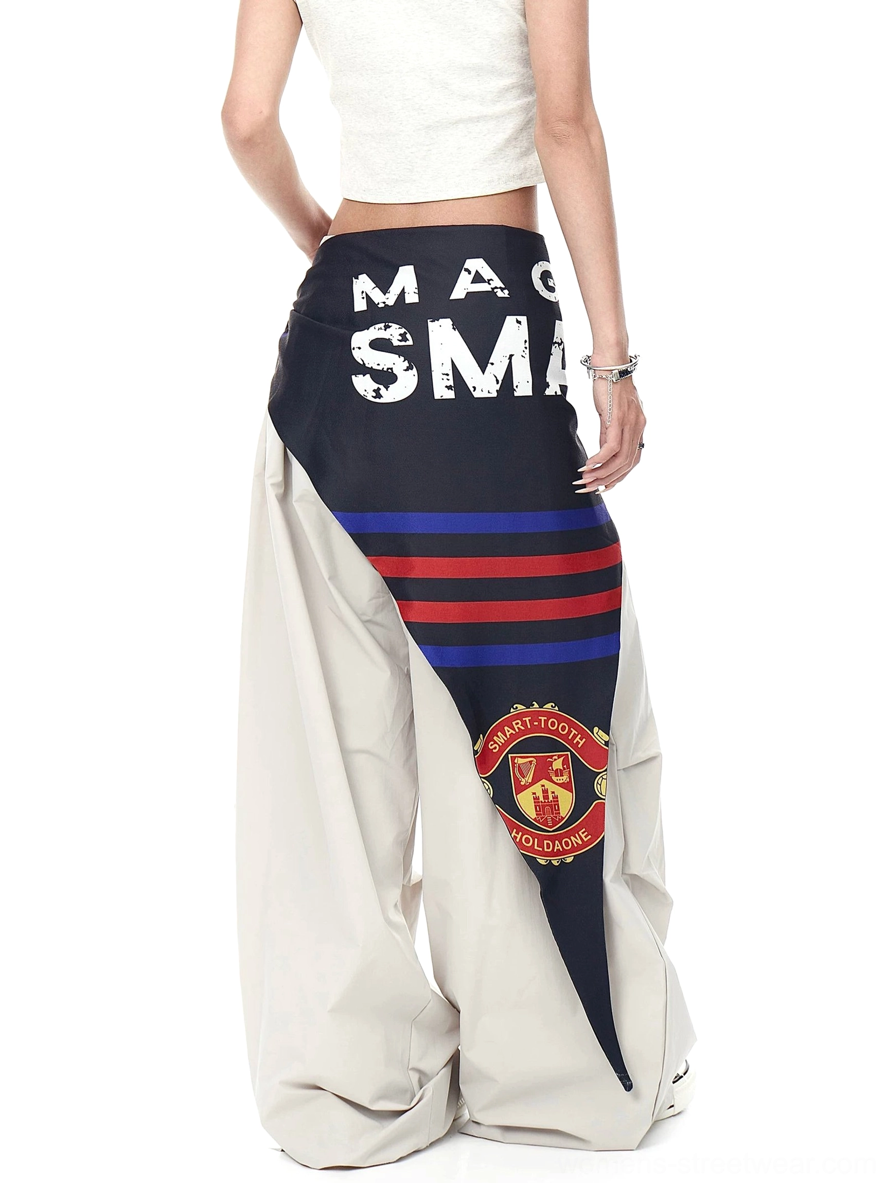 Side front view of light beige streetwear cargo pants with oversized parachute legs, printed varsity scarf, letter graphics, and football-inspired badge detail