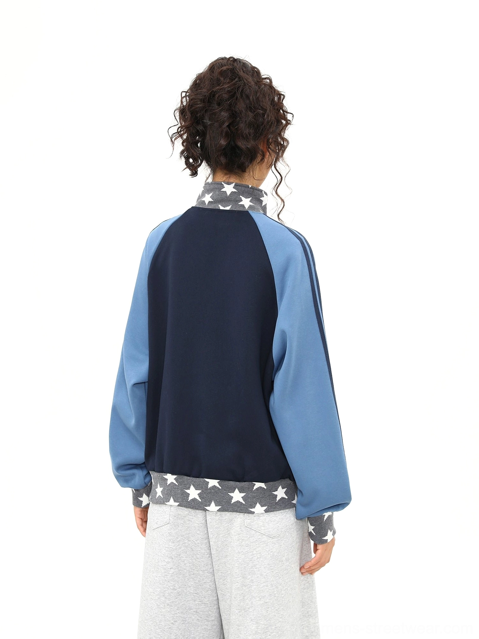 Rear view of a navy colorblock varsity track jacket showing blue striped sleeves and star print ribbed hem