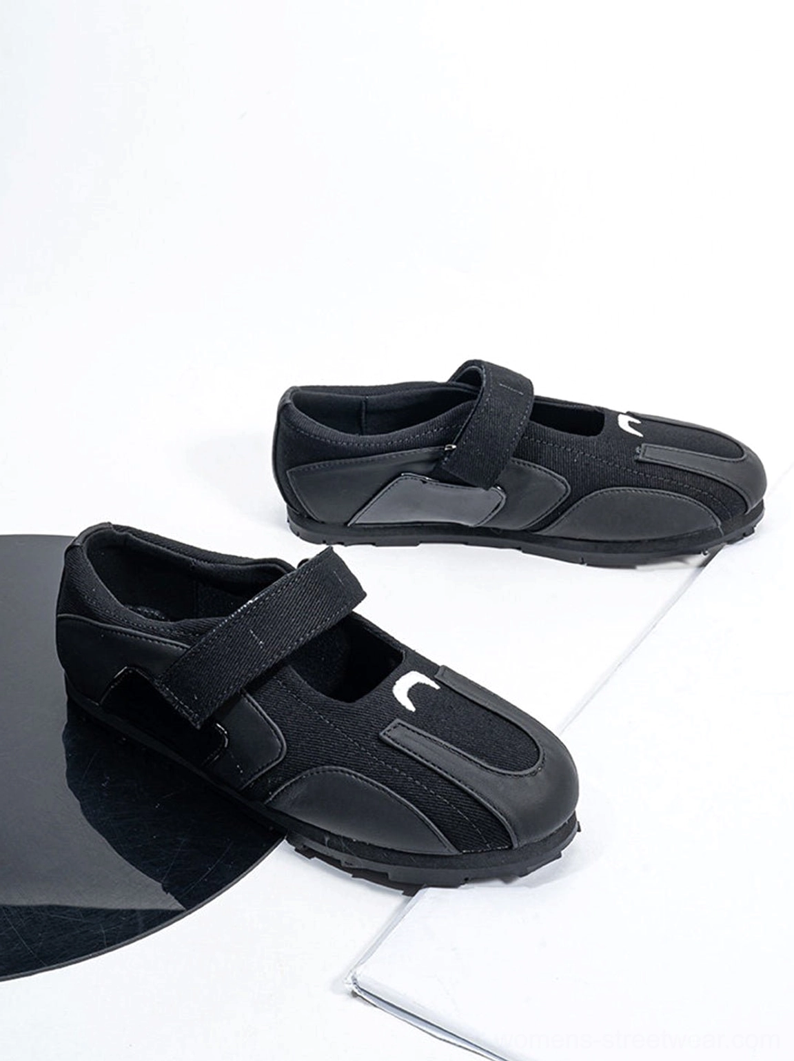 All-black low-profile sport ballet Mary Jane sneakers displayed as a pair in minimalist studio